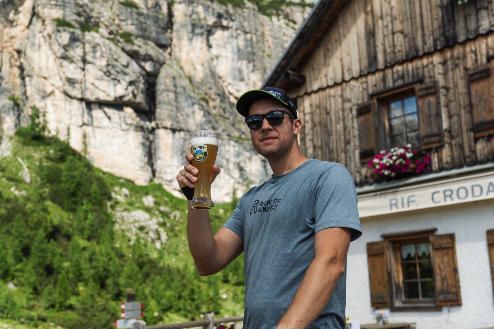 Runner raising a beer outside a Dolomites rifugio