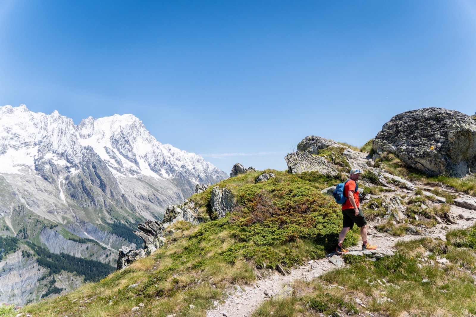 Runner on a ridge trail facing the snow-covered Mont Blanc massif